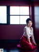 A woman in a white shirt and red skirt sitting on the floor.