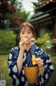 A woman in a blue and white kimono blowing bubbles.