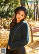 A woman wearing a green sweater and a black hat.