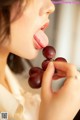 A woman sticking out her tongue while holding a bunch of grapes.