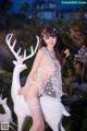 A woman in lingerie posing next to a white deer.