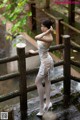 A woman in a white dress standing on a wooden bridge.