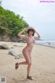 A woman in a bikini and hat on a beach.