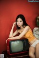 A woman sitting on top of a table next to a television.