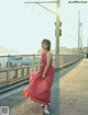 A woman in a red dress is walking across a bridge.