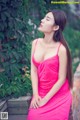 A woman in a pink dress sitting on a brick wall.