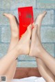 A pair of women's legs holding a red envelope.