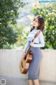 A woman in a blue and white striped shirt holding a guitar.