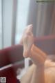 A woman's bare feet on a red couch.