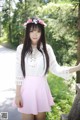 A woman in a white top and pink skirt posing for a picture.