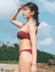 A woman in a red bikini standing on a beach.