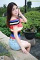 A woman in a colorful top and denim shorts posing for a picture.