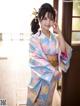 A woman in a blue and pink kimono posing for a picture.