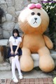 A woman sitting next to a giant teddy bear.