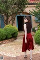 A woman in a red skirt is standing in front of a house.