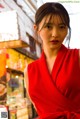 A woman in a red dress standing in front of a store.