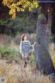 A woman standing next to a tree in a field.