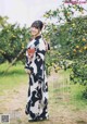 A woman in a kimono standing in front of an orange tree.