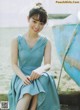 A woman in a blue dress sitting on a wooden bench.