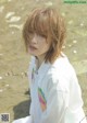 A woman in a white shirt sitting on a beach.