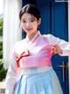 A woman in a pink and blue hanbok posing for a picture.