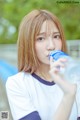 A young woman drinking water from a bottle.