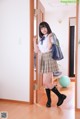 A woman in a school uniform is standing in front of a door.