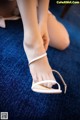 A woman is putting on a pair of white sandals.
